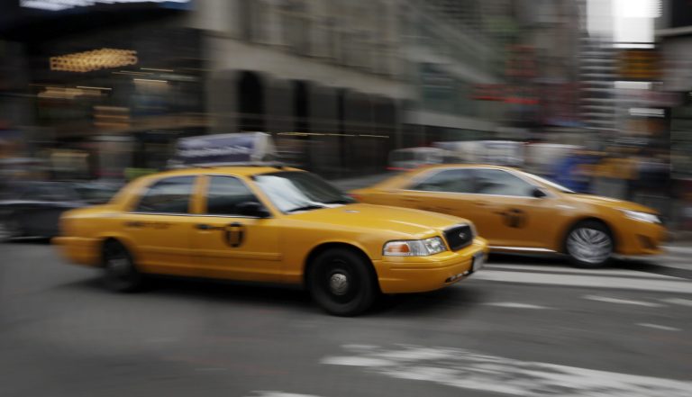 FILE - In this Thursday, Feb. 27, 2014 file photo, New York City taxis drive through New York's Times Square. The car-hailing service Uber is taking on New York City's taxis, temporarily dropping some of its prices by 20 percent starting Monday, July 7, 2014. (AP Photo/Richard Drew)