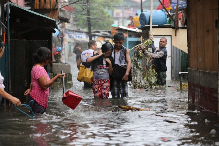 Residents wade through floods as they go back to their home while Typhoon Rammasun batters suburban Quezon city, north of Manila,  Philippines on Wednesday, July 16, 2014. Typhoon Rammasun knocked out power in many areas but it spared the Philippine capital, Manila, and densely-populated northern provinces from being directly battered Wednesday when its fierce wind shifted slightly away, officials said.  (AP Photo/Aaron Favila)