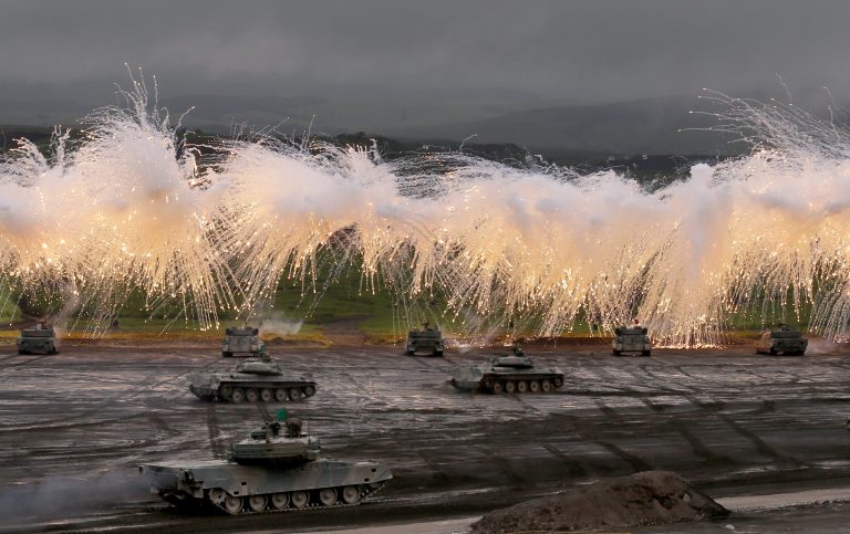 Japan Ground Self-Defense Force's Type-89 armored combat vehicles flare up a smoke screen during an annual live firing exercise at Higashi Fuji range in Gotemba, southwest of Tokyo, Tuesday, Aug. 19, 2014. (AP Photo/Shizuo Kambayashi)
