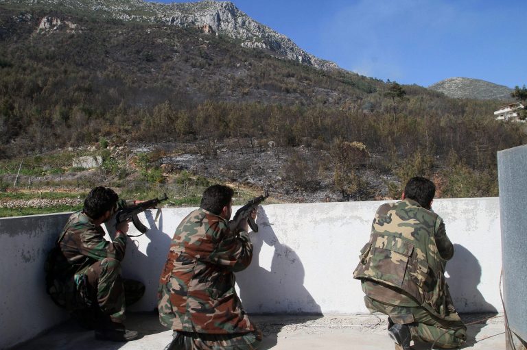 In this photo taken Thursday, March 27, 2014, Syrian government soldiers take position during clashes with rebels in Misherfeh town in the province of Latakia, Syria. Syrian forces on Thursday bombarded rebel positions with artillery and warplanes in the Mediterranean coastal province of Latakia, trying to push back opposition fighters who over the past week made rare territorial gains in President Bashar Assad's ancestral heartland. (AP Photo)