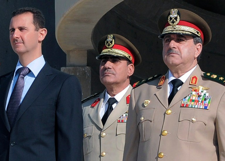 Syrian President Bashar Assad, left, stands with the country's defense minister, right, during a ceremony in Damascus, Syria, in October 2011. (AP Photo/SANA, File)