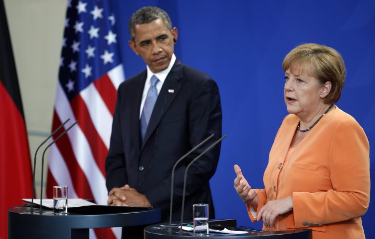 US President Barack Obama, left,  listens  as German Chancellor Angela Merkel, right, addresses  the media during a press conference at the chancellery in Berlin Wednesday, June 19, 2013. On the second day of his visit to Germany Obama met with German President Joachim Gauck and Chancellor Merkel before delivering a speech at Brandenburg Gate. (AP Photo/Michael Sohn)
