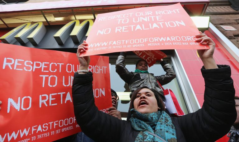 People hold signs during a protest for better wages for fast food workers outside a McDonald's restaurant in Harlem on April 4. (Mario Tama/Getty Images)