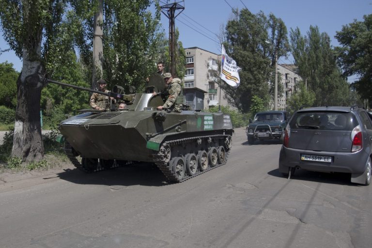 FILE - In this Sunday May 18, 2014 file photo pro-Russian militants drive atop of an armored personal carrier as they guard streets in Slovyansk, eastern Ukraine. The struggling interim government in Kiev has been counting on the election to install a president who would be seen as a legitimate successor to Viktor Yanukovych, who fled to Russia in February after months of street protests. But the long-anticipated election may not be considered legitimate by Russia, the West or Ukrainians themselves if people in a large part of the country are unable or unwilling to cast their ballots. (AP Photo/Alexander Zemlianichenko, File)