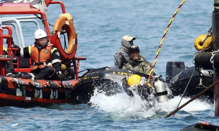 A diver jumps into the sea to look for people believed to have been trapped in the sunken Sewol ferry near buoys which were installed to mark the vessel in the water off the southern coast near Jindo, South Korea, Friday, April 25, 2014. Frustrated relatives of the scores of people still missing from the sinking of the ferry staged a marathon confrontation with the fisheries minister and the coast guard chief, surrounding the senior officials in a standoff that lasted overnight and into Friday morning as they vented their rage at the pace of search efforts.(AP Photo/Yonhap)  KOREA OUT
