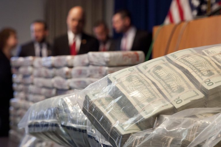 Sacks of money, right, worth $2 million, and 154 pounds of heroin, left, worth at least $50 million, are displayed at a Drug Enforcement Administration news conference, Tuesday, May 19, 2015 in New York. (AP Photo/Mark Lennihan)
