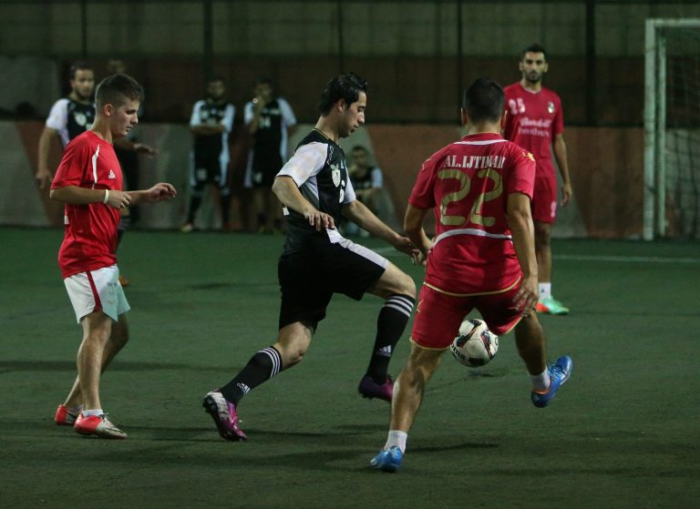 In this photo taken on Tuesday June 10, 2014, Mohammed Meslamani, center, a player of Syrian opposition team, made up of former professional and national youth soccer players who became refugees in Lebanon, fights for the ball against Lebanese players, left and right, during a match against a Lebanese team, at a makeshift pitch in Tripoli, north Lebanon. The squad of refugee players are formally known as the Free Syrian National Team. On rare occasions, when they play against a local club in the northern Lebanese city of Tripoli, they sport their version of the national uniform: black-and-white jerseys adorned with a Syrian revolutionarily flag with three _ instead of two_ stars, pressing against their hearts.  (AP Photo/Hussein Malla)