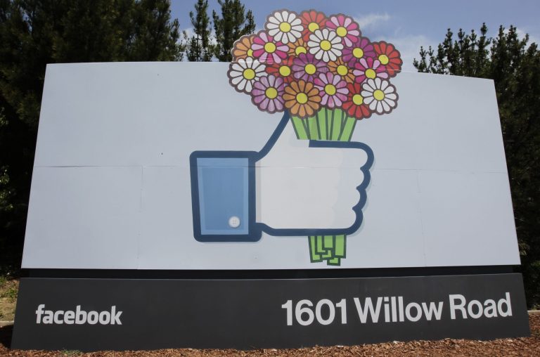 FILE - In this Sunday, May 13, 2012, file photo, flowers are added to a Facebook sign in front of Facebook headquarters in Menlo Park, Calif. (AP Photo/Paul Sakuma, File)