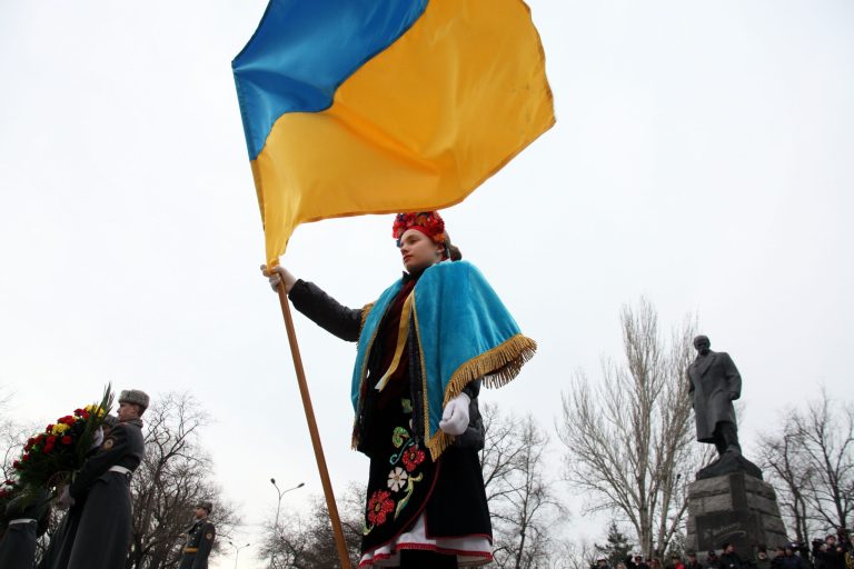 FILE - In this Sunday, March 9, 2014 file photo a young Ukrainian woman holds a Ukrainian flag during celebrations of the 200th birthday anniversary of Ukrainian poet Taras Shevchenko in the Black Sea port of Odessa, Ukraine. The monument to the poet is in the background. Ukraine, a land the size of France with a population of 46 million, has historically been a massive prize in the heart of Europe. The site of the ancient Slavic state, the Kievan Rus, it was the regional cradle of Orthodox Christianity. Over centuries, parts of Ukraine have belonged to Poland, the Austro-Hungarian Empire, Russia and the Soviet Union. (AP Photo/ Sergei Poliakov, File)