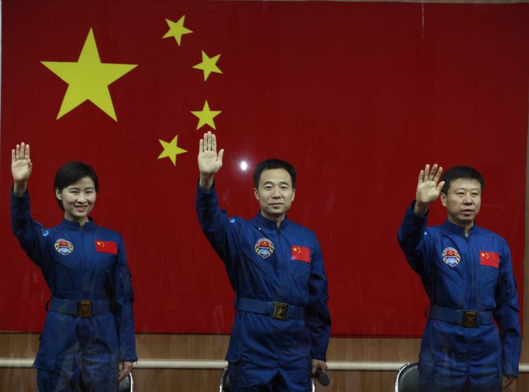   Chinese astronauts from left., Liu Yang, Jing Haipeng and Liu Wang wave from behind a glass enclosure as they meet the press at the Jiuquan satellite launch center near Jiuquan in western China's Gansu province, Friday, June 15, 2012. China will send its first woman into space Saturday along with two other astronauts to work on a temporary space station for about a week, in a key step toward becoming the only third nation to set up a permanent base in orbit. (AP Photo/Ng Han Guan)  