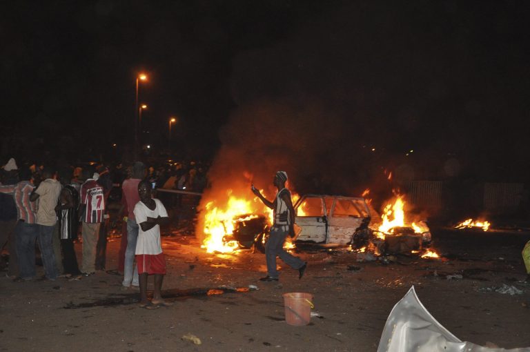 People gather at the site of a car bomb explosion in Abuja, Nigeria, Thursday, May 1, 2014. A car bomb exploded on a busy road in Nigeria's capital late Thursday, killing at least nine people days before the city is to host a major international economic forum. (AP Photo/Gbemiga Olamikan)