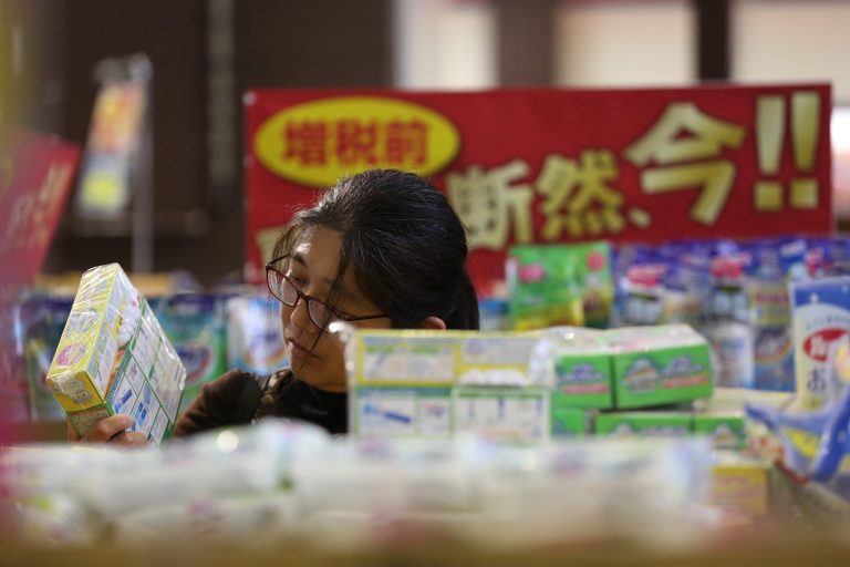In this March 27, 2014 photo, a customer looks at a product at a bargain sale prior to the tax hike at a supermarket in Shin-Urayasu.  Japanese retailers are luring customers with promises of steep discounts ahead of a sales tax hike Tuesday, April 1,  that economists expect to slow but not derail the recovery of the world's third-largest economy. Japan's sales tax will rise from 5 percent to 8 percent. (AP Photo/Eugene Hoshiko)