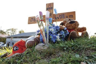 Jose Luis Magana/AP
A cross and flowers are placed at the side of the road in Clarksburg, Md., on Tuesday where Maryland police found remains that they believe are those of a missing boy whose mother was discovered slain.