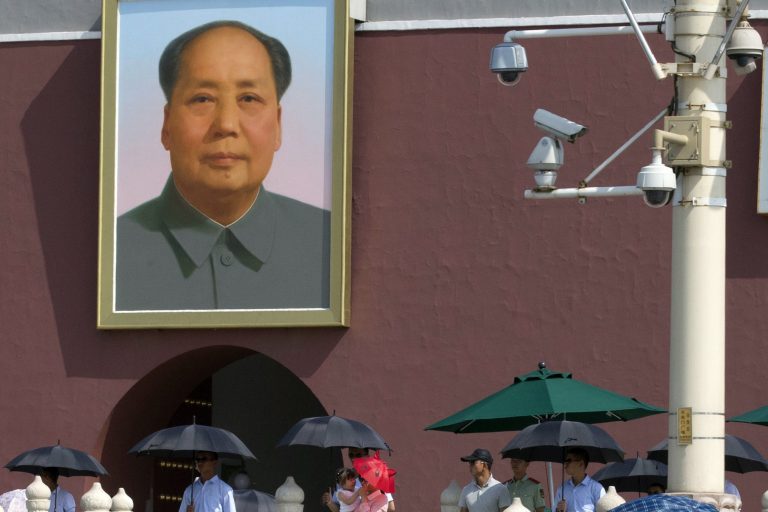 A woman and child pass by uniformed and plainclothes security personnel with umbrellas and security cameras near a portrait of late Chinese leader Mao Zedong on Tiananmen Gate in Beijing Tuesday, June 3, 2014. Beijing put additional police on the street and detained government critics Tuesday as part of a security crackdown on the eve of the 25th anniversary of the crushing of pro-democracy protests centered on the capital's Tiananmen Square. (AP Photo/Ng Han Guan)
