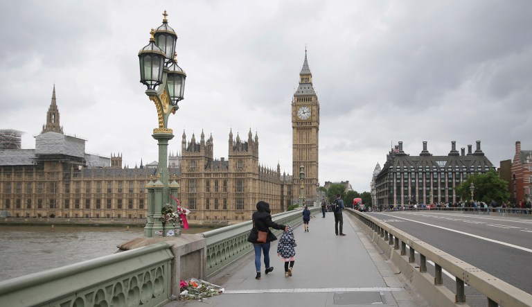 A flower tribute is placed behind newly installed barriers on Westminster Bridge in London. A series of attacks described as terrorism killed several people and injured more than 40 others in the heart of London in March. (AP Photo/Tim Ireland)