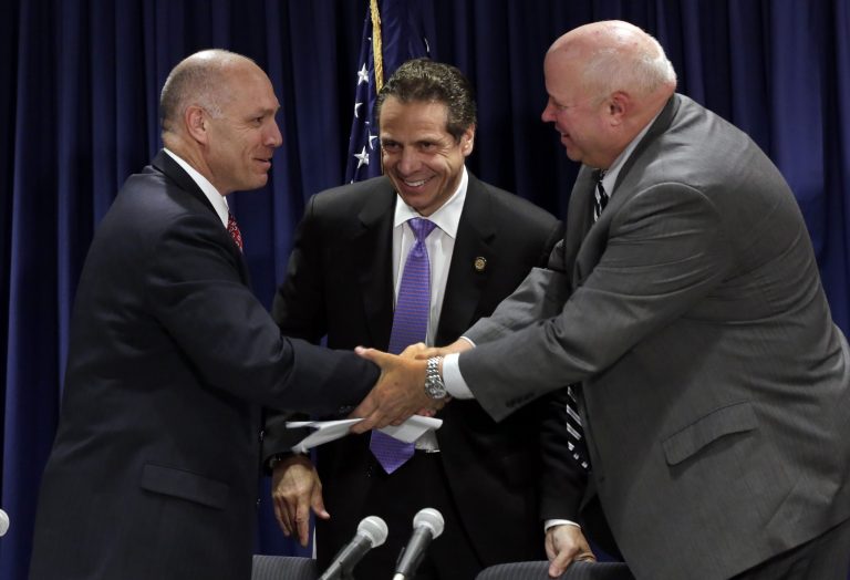 Anthony Simon, general chairman of the United Transportation Union, left, and Metropolitan Transportation Authority Chairman Thomas Prendergast, right, shake hands in front of Gov. Andrew Cuomo after a tentative labor agreement was reached at Cuomo's office in New York on Thursday, July 17, 2014. (AP Photo/Richard Drew)