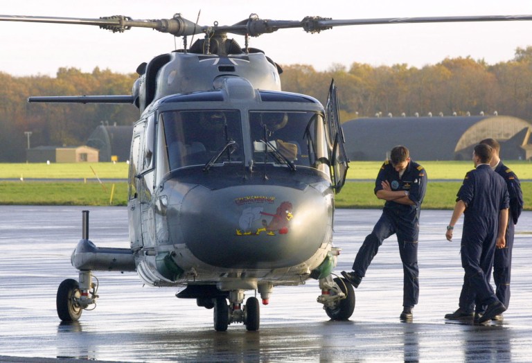 FILE - The Nov. 19, 2001 file photo shows German Navy soldiers standing beside a Sea Lynx helicopter on the air base Upjever, northwestern Germany. German military struggles with hardware problems. German defense officials have been left red-faced after a series of breakdowns delayed the first shipment of arms to Kurdish fighters in Iraq.(AP Photo/Joerg Sarbach, file)