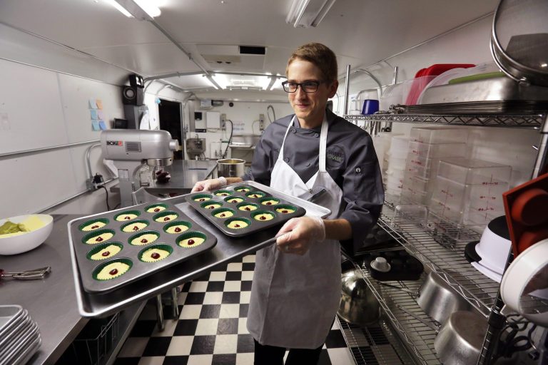 FILE - In this June 19, 2014, file photo, chef Alex Tretter carries a tray of cannabis-infused peanut butter and jelly cups to the oven for baking at Sweet Grass Kitchen, a well-established Denver-based gourmet marijuana edibles bakery which sells its confections to retail outlets throughout the state. Colorado marijuana regulators have drafted an emergency rule aimed at making it easier for new marijuana users to tell how much pot they are eating. (AP Photo/Brennan Linsley, File)