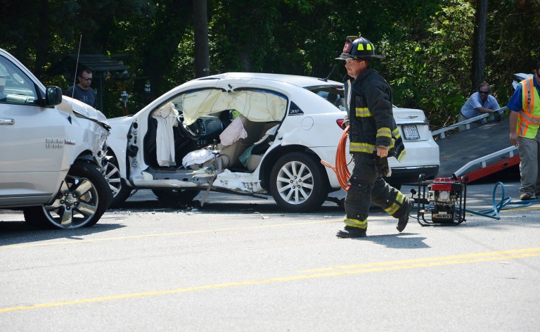 FILE - This May 13, 2014 file shows a North Lenoir, N.C. firefighter taking equipment back to the truck after a woman, pinned in her white vehicle, was rescued by the jaws of life, in Kinston, N.C. The economic and societal harm from motor vehicle crashes amounted to a whopping $871 billion in a single year, according to a study released Thursday by the National Highway Traffic Safety Administration. The study examined the economic toll of car and truck crashes in 2010, when 32,999 people were killed, 3.9 million injured and 24 million vehicles damaged. Those deaths and injuries were similar to other recent years.(AP Photo/Daily Free Press, Janet S. Carter)