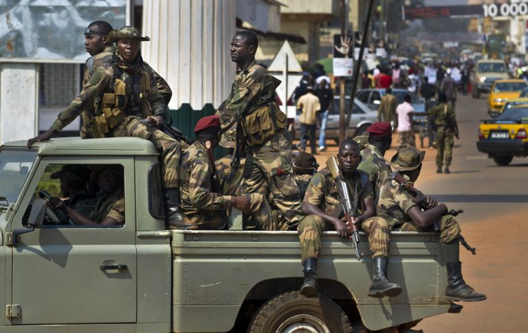 FILE - In this Jan. 5, 2013 file photo, government security forces in a pickup truck drive past a demonstration calling for peace as negotiators prepare for talks with rebels from the north, in downtown Bangui, Central African Republic Saturday. On Friday, March 22, rebels took the town of Damara, beginning a new march to take the capital, Bangui, said a rebel spokesman. Panic spread throughout the capital, with the neighborhoods closest to the northern gate of the city emptying out, as frightened residents locked up their shops, packed their bags and yanked their children out of school. Banks and government offices closed early.(AP Photo/Ben Curtis, File)