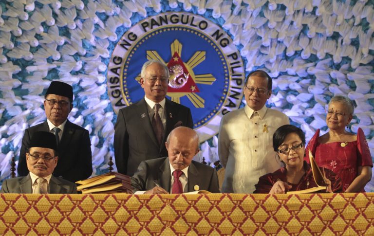 In this handout photo released by the Malacanang Photo Bureau, President Benigno S. Aquino III, back row secon from right, Malaysian Prime Minister Najib Razak, back row second from left, Moro Islamic Liberation Front (MILF) Chairman, Al Haj Murad Ebrahim, back row left, and Secretary Teresita Quintos-Deles, seated left, Presidential Adviser on the Peace Process, back row right, witness the signing of the Comprehensive Agreement on the Bangsamoro (CAB) by MILF chief negotiator Mohagher Iqbal, Datu Tengku Gnafar, seated center, and Miriam Coronel Ferrer, seated right,  of the Philippine government in a ceremony at the Malacanang Presidential Palace in Manila, Philippines on Thursday March 27, 2014. The Philippine government signed a peace accord with the country's largest Muslim rebel group on Thursday, the culmination of years of negotiations and a significant political achievement for President Aquino.(AP Photo/Malacanang Photo Bureau, Benhur Arcayan)