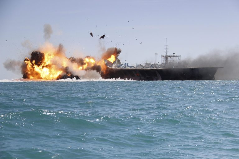 In this picture released by the Iranian Tasnim news agency on Wednesday, Feb. 25, 2015, a replica of a U.S. aircraft carrier is exploded by the Revolutionary Guard's speedboats during large-scale naval drills near the entrance of the Persian Gulf, Iran. The drill, named Great Prophet 9, was the first to involve a replica of a U.S. carrier. (AP Photo/Tasnim News)