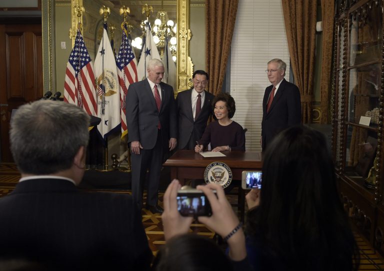 Transportation Secretary Elaine Chao sits down to sign the affidavit of appointment as Vice President Mike Pence, her father James Chao, and her husband Senate Majority Leader Mitch McConnell of Ky., watch, in veeps ceremonial office in the Eisenhower Executive Office Building in the White House complex in Washington, Tuesday, Jan. 31, 2017. (AP Photo/Susan Walsh)