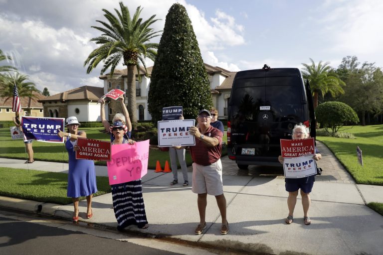 Supporters of Republican presidential candidate Donald Trump hold signs as Democratic presidential candidate Hillary Clinton's motorcade passes after a fundraising event in Lake Mary, Fla., Wednesday, Sept. 21, 2016. (AP Photo/Matt Rourke)