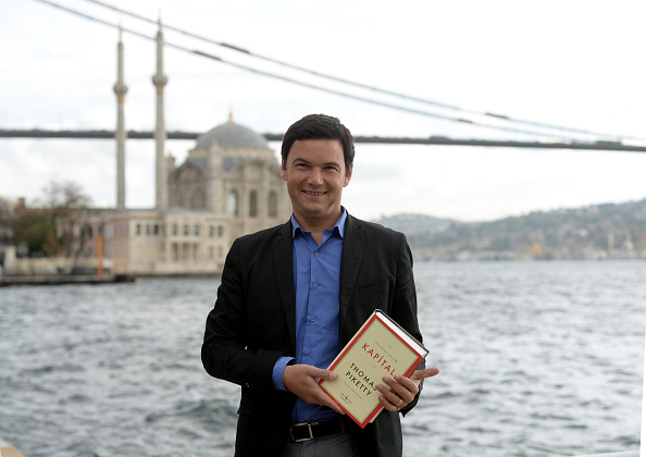 French economist Thomas Piketty poses near the Bosphorus with his book Capital in the Twenty-First Century's Turkish translation in Istanbul, Turkey on November 20, 2014. (Photo by Metin Pala/Anadolu Agency/Getty images)