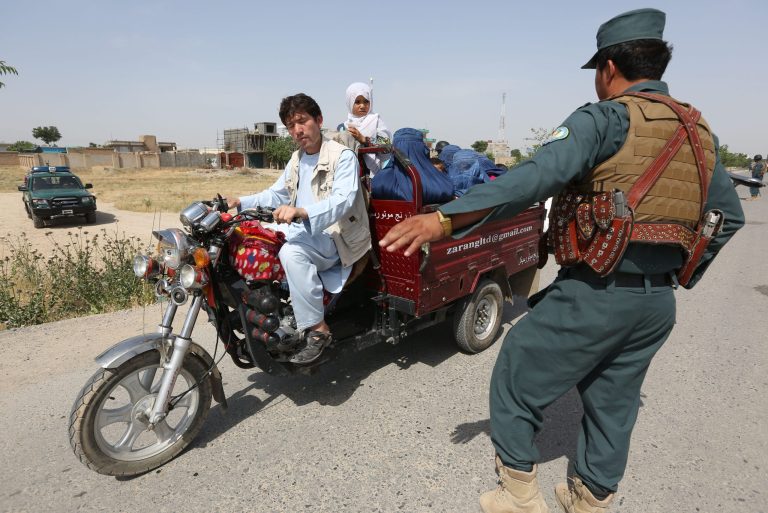 In this Friday, May 22, 2015 photo, an Afghan police stops a motorbike at a checkpoint on the outskirts of Kunduz, north of Kabul, Afghanistan. (AP Photo/Rahmat Gul)
