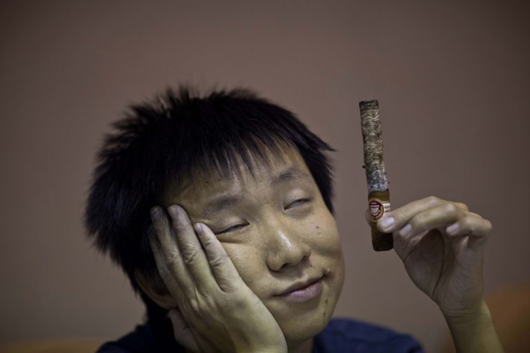 A participant in the competition for the longest ash is dizzied by the smoke of his cigar during the XVI Cuba Cigar festival, in Havana, Cuba, Thursday, Feb. 27, 2014. Cigar enthusiasts from around the world come to Cuba during the annual Cigar Festival to visit tobacco farms and factories and savor new cigar brands. (AP Photo/Ramon Espinosa)