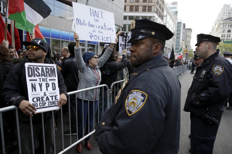 Demonstrators march past police officers in New York, Friday, May 1, 2015. About 1,000 protesters decrying police brutality marched in Manhattan at a May Day rally that took on a new message amid national outrage over a Baltimore man's death in police custody. (AP Photo/Seth Wenig)