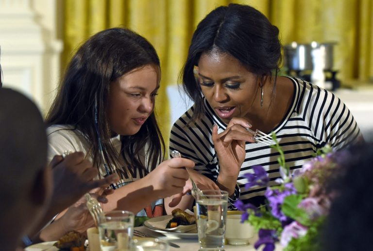 In this Tuesday, Oct. 14, 2014, file photo, first lady Michelle Obama and a student look over their plates as they eat lunch in the East Room of the White House following the annual fall harvest of the White House Kitchen Garden in Washington. (AP Photo/Susan Walsh, File)