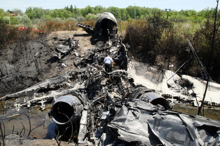 A National Transportation Safety Board official looks through the wreckage at the scene Monday, June 2, 2014, in Bedford, Mass., where a plane plunged down an embankment and erupted in flames during a takeoff attempt at Hanscom Field Saturday night. Lewis Katz, co-owner of the Philadelphia Inquirer and six other people died in the crash. (AP Photo/Boston Herald, Mark Garfinkel, Pool)