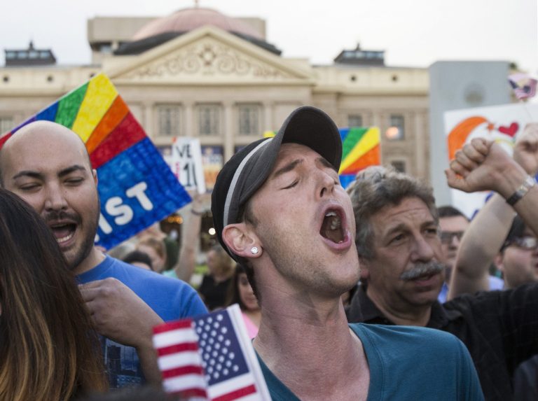 Demonstrators including Christopher Bullock, center, celebrate after hearing that Arizona Gov. Jan Brewer was going to veto SB1062, Wednesday, Feb. 26, 2014, in Phoenix. The bill is designed to give added protection from lawsuits to people who assert their religious beliefs in refusing service to gays. MARICOPA COUNTY OUT; MAGS OUT; NO SALES.