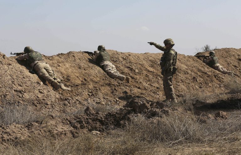 A U.S. soldier, second right, helps Iraqi security forces improve shooting skills in a military exercise as U.S. forces train them in Taji, north of Baghdad, Iraq, Saturday, March 21, 2015. (AP Photo/Karim Kadim)
