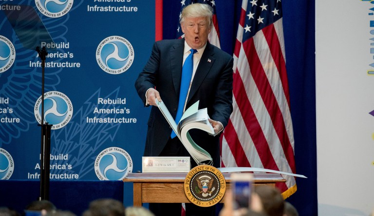 Speaking at DOT on Friday, Trump said he met with people responsible for their states' economic development and roadways, including a man who showed the president a massive binder containing a costly environmental report that held up road construction. (AP Photo/Andrew Harnik)