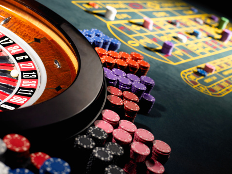 Gambling chips stacked around roulette wheel on gaming table