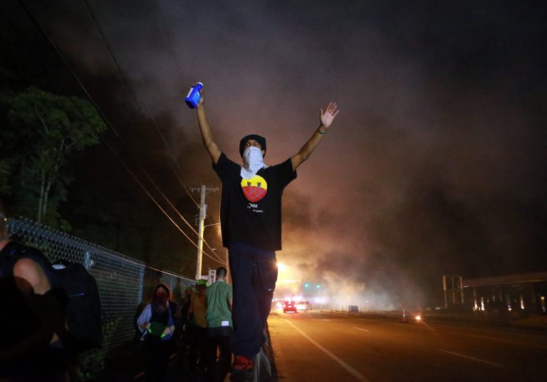 A protester raises his arms following a clash with police Monday in Ferguson, Mo. The Aug. 9 shooting of Michael Brown by police has touched off rancorous protests in the St. Louis suburb. (AP Photo/St. Louis Post-Dispatch, Christian Gooden)