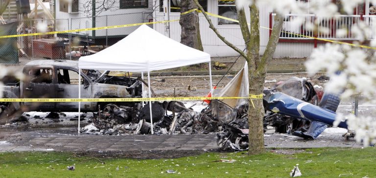 Caution tape surrounds the charred wreckage of a news helicopter and two vehicles after the chopper crashed into a city street near the Space Needle, Tuesday, March 18, 2014, in Seattle. Two people were killed and another critically injured. (AP Photo/Stephen Brashear)