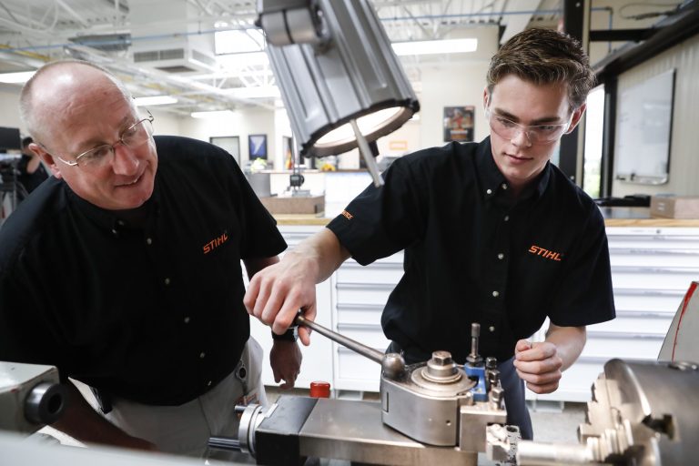 Apprentice Ryan Buzzy, right, works with Skip Johnson, a trainer for the Stihl Inc. apprenticeship program, on a metalworking lathe in their training area at the Stihl Inc. manufacturing facility in Virginia Beach, Va., on May 25. (AP Photo/John Minchillo)