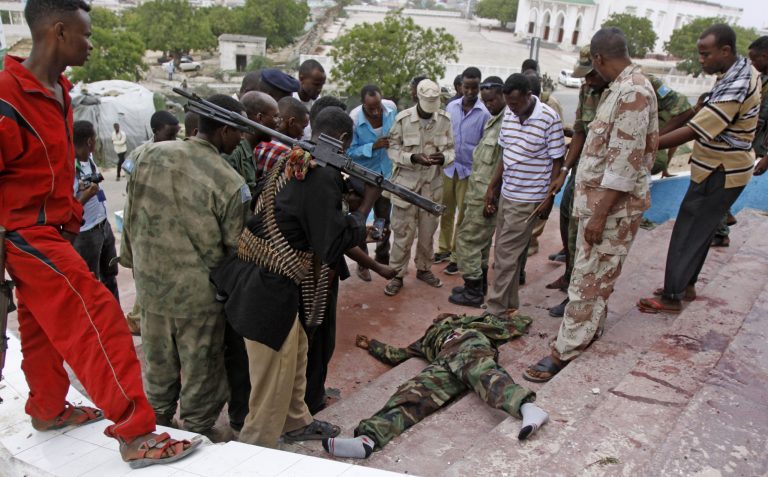 Somali soldiers gather around the dead body of an Al Shabab fighter who was killed during an attack on Somalia's parliament,  Saturday, May 24, 2014.  Militants in Mogadishu on Saturday carried out a multi-pronged, complex attack against the country's parliament building involving a car bomb, suicide bomber and gunmen on foot, police said. Several people were killed, including six attackers and one soldier who tried to stop a suicide bomber from entering the building, said police Capt. Mohamed Hussein. (AP Photo/Farah Abdi Warsameh)
