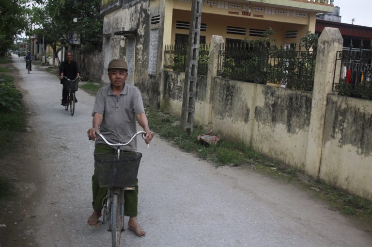 In this April 17, 2014 photo, men cycle through Vu Hoi, a village in northern Vietnam where hundreds of women have migrated to Taiwan and other destinations over the past 15 years. Women account for a rising share of the workers leaving rural Asia in search of higher salaries in the factories and flashy megacities of more-developed countries, leaving behind legions of so-called 