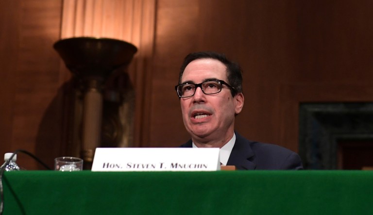 Treasury Secretary Steven Mnuchin testified as stock markets gyrated wildly, after falling steeply Friday and Monday. He monitored stock prices on his phone as representatives questioned him. (AP Photo/Susan Walsh)