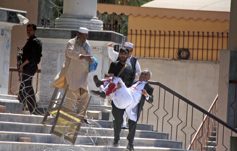 A Pakistani police officer carries an injured man at the site of a suicide bombing attack towards an ambulance, unseen, outside a court complex in Peshawar, Pakistan, Monday, March 18, 2013. A pair of suicide bombers attacked a court complex in the northwestern Pakistani city of Peshawar on Monday, killing at least three people and wounding over two dozen, police said. (AP Photo/Mohammad Sajjad)