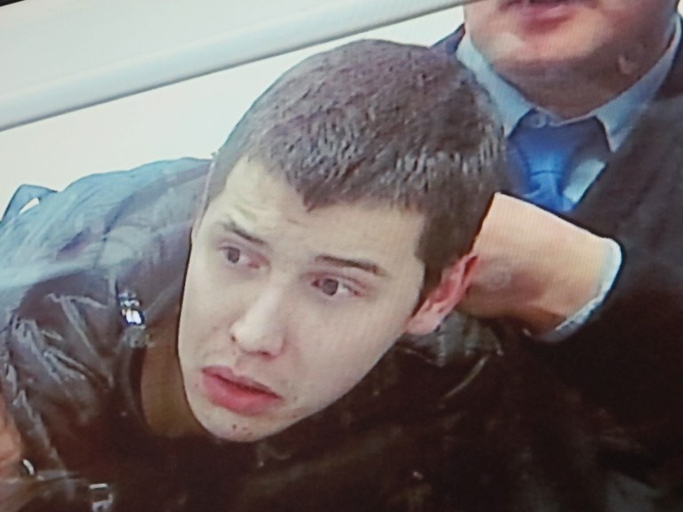  This photo of a relayed televised image from a courtroom shows Vladislav Chelakh struggling with guards Tuesday, Dec. 11, 2012, during the last day of his trial in the southern Kazakhstan city of Taldykorgan. Chelakh, a conscript in Kazakhstan's army, is accused of killing 14 fellow soldiers and a park ranger in a May massacre that shocked the Central Asian nation. (AP Photo/Peter Leonard)  
