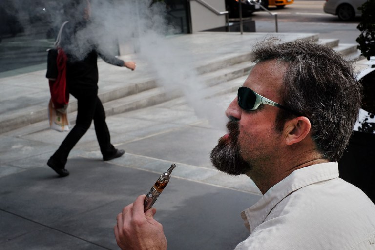 A man vaping on the street.