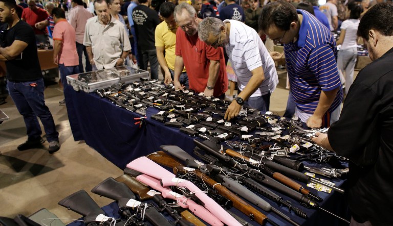 People shop for guns at a gun show. Current laws prohibit federally licensed firearm dealers from selling long gun rifles or shotguns to someone under 18, and cannot sell handguns to someone under 21. (AP Photo/Lynne Sladky)