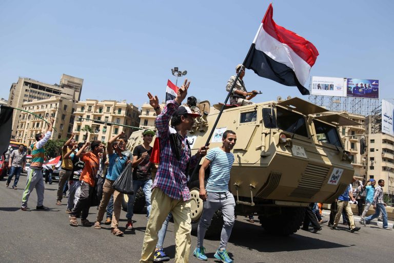 Egyptians wave the national flag and walk alongside a military vehicle. (AP Photo/Mohamed Elraai)