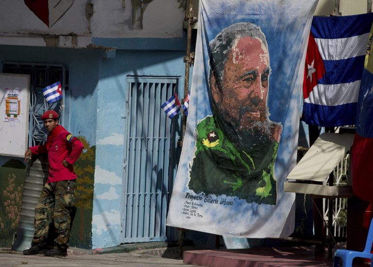 A Venezuelan militia member stands next a banner of Fidel Castro in the 23 de Enero neighborhood of Caracas, Venezuela, Saturday, Nov. 26, 2016. 